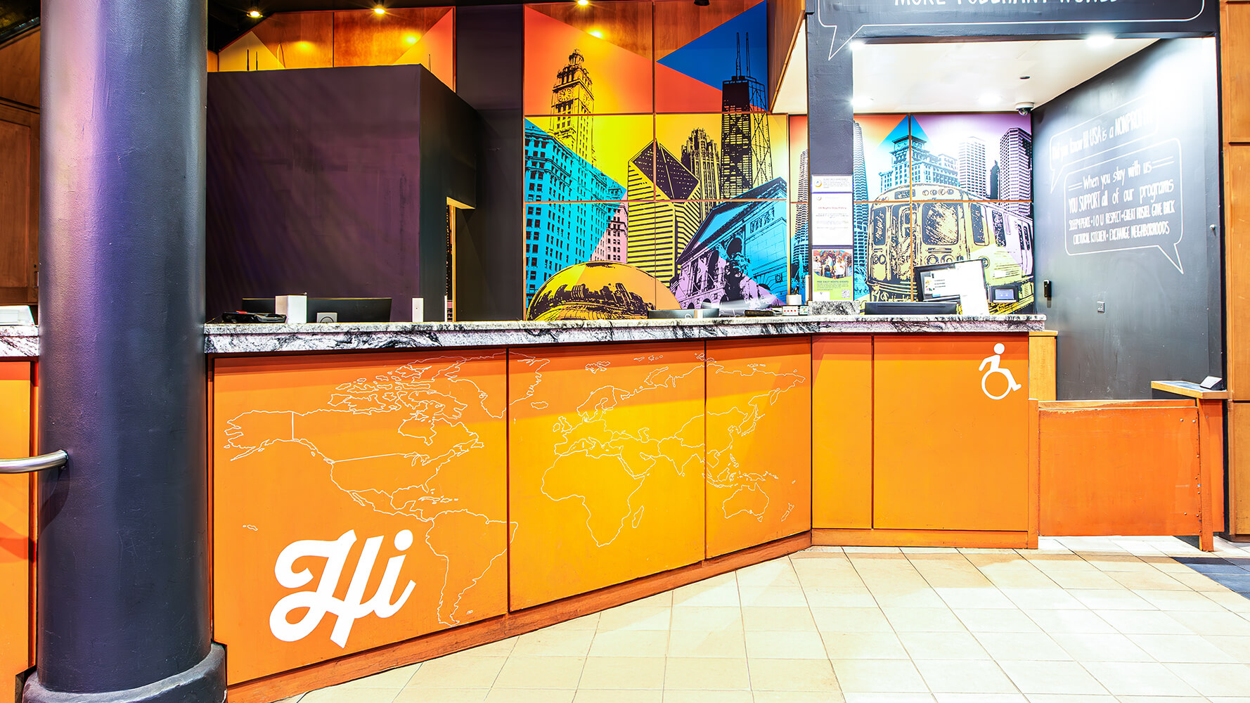The airy lobby of HI Chicago hostel with a large orange front desk and colorful murals behind it