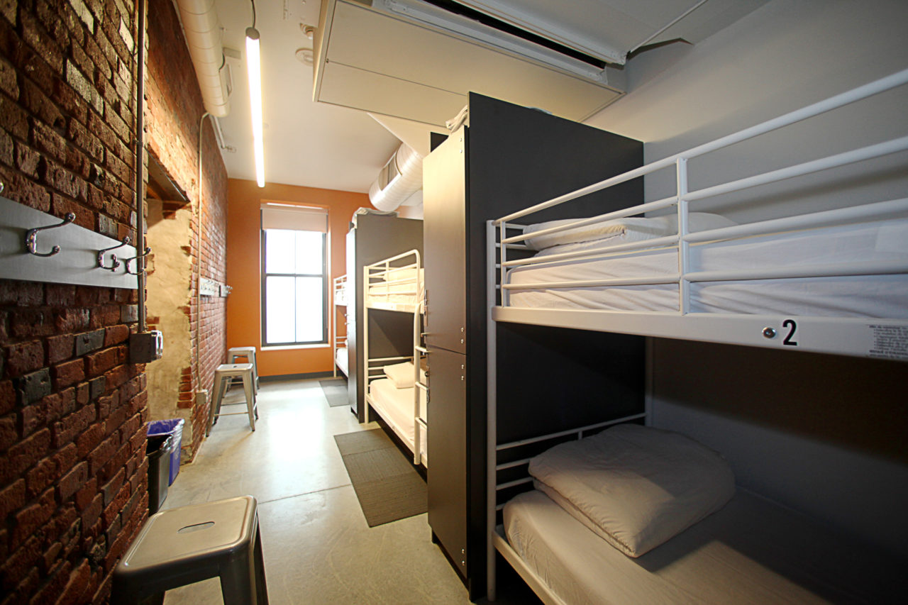 six twin-sized bunk beds in a room with exposed brick walls