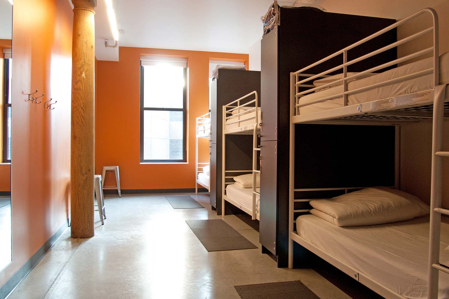 a dorm room at HI Boston Hostel with three sets of twin-sized bunkbeds, with privacy walls between each set of beds.