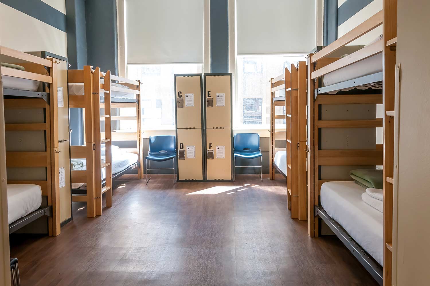 a dorm room at HI Chicago hostel with four sets of bunk beds, secure lockers for guest belongings, and two large windows