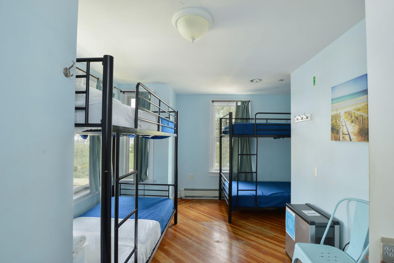 an airy dorm room at HI Hyannis hostel on cape cod with four freshly made bunk beds.