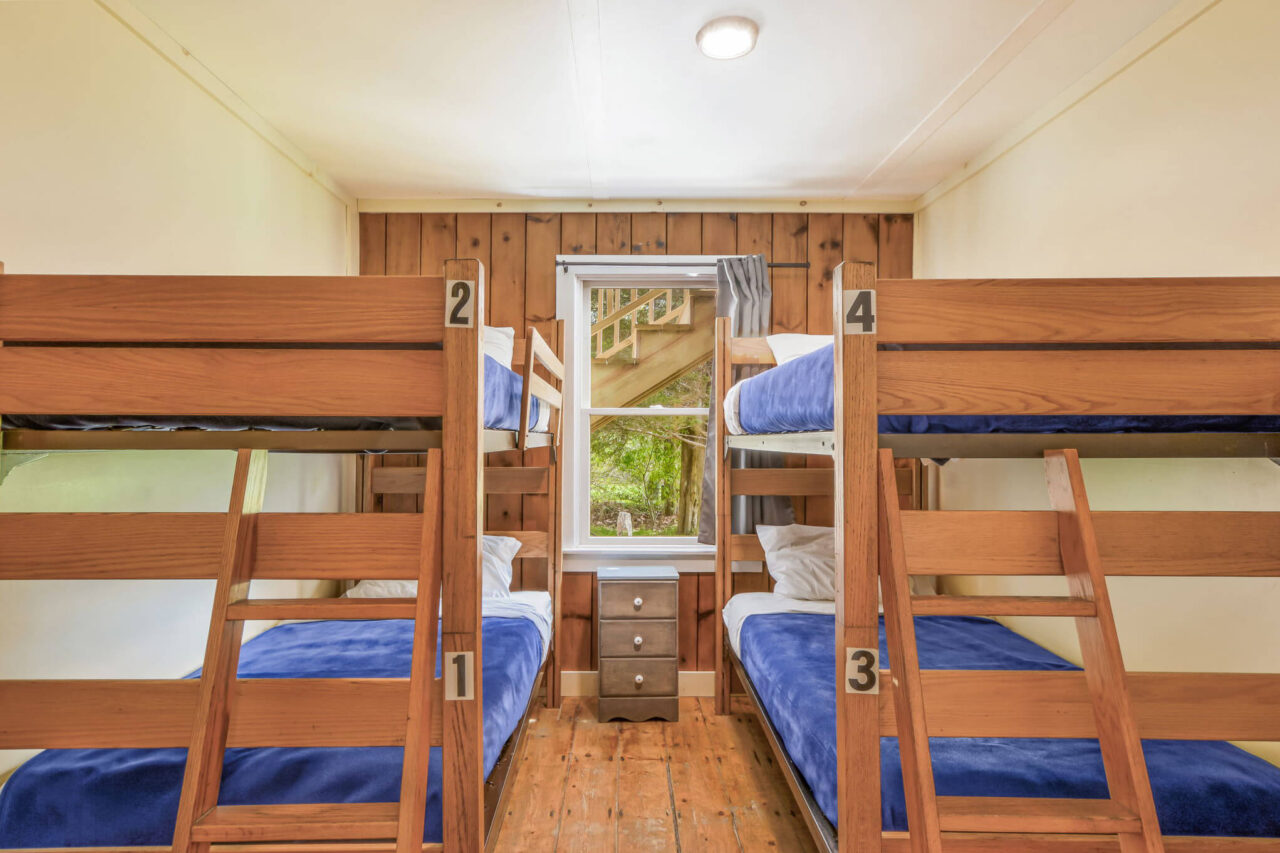 The private 4-bed room at HI Martha's Vineyard hostel has two sets of twin-sized bunk beds, with a window overlooking the trees.