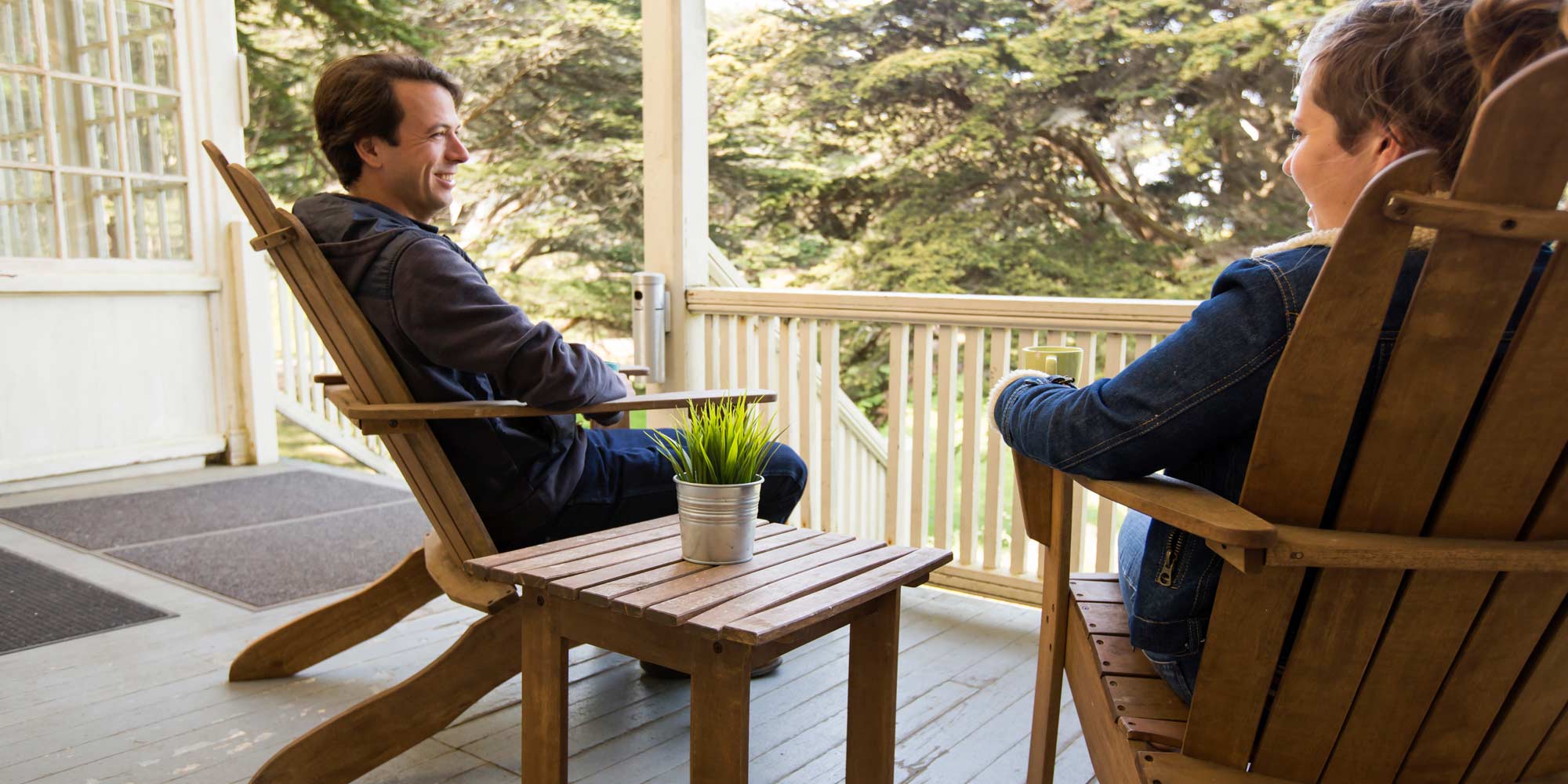 Man and woman relaxing in chairs on porch at HI Marin Headlands hostel.