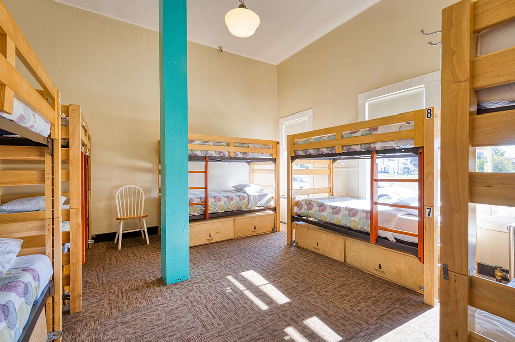 a spacious dorm room at HI San Francisco Fisherman's Wharf hostel with five sets of freshly made wooden bunk beds