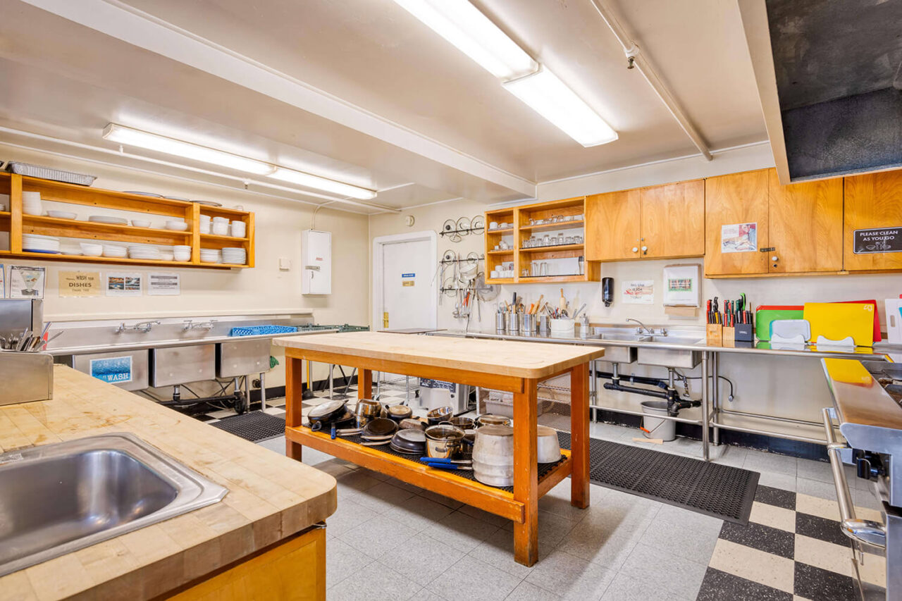 HI San Francisco Fisherman's Wharf hostel features a fully equipped guest kitchen. Seen here are multiple sinks, burners, and chopping surfaces in a large, clean kitchen for group use.