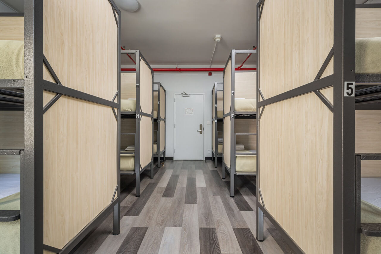 A clean and modern shared dorm room at HI New York City hostel with privacy screens on each of the 12 bunks.