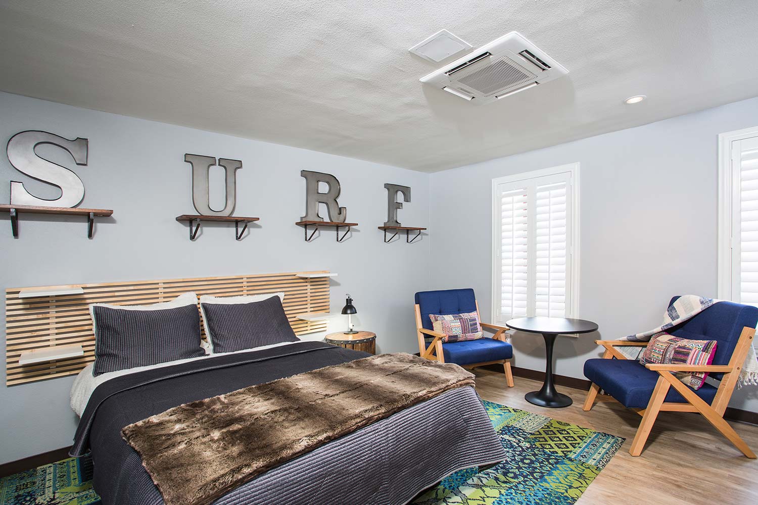 the executive suite at HI Los Angeles Santa Monica hostel is a large private room with a queen-sized bed, seating area, large ensuite bathroom, and beach-themed decor