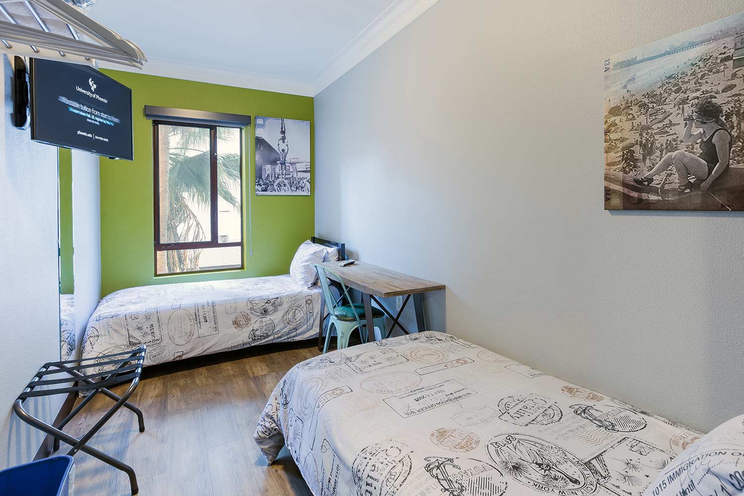 a small private room at HI Los Angeles Santa Monica hostel with two freshly made twin-sized beds, a luggage rack, and a TV mounted on the wall