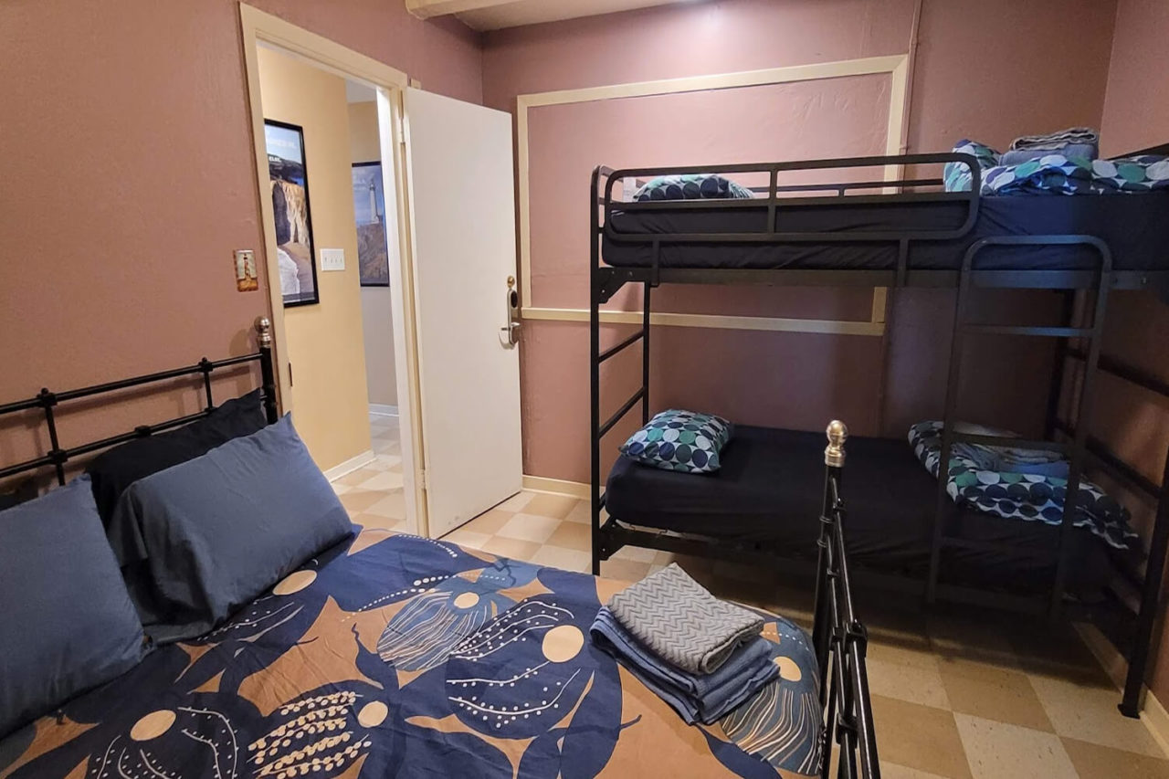 a private room at HI Point Montara Lighthouse hostel with one full-sized bed and one set of twin-sized bunks that can accommodate up to 4 people.