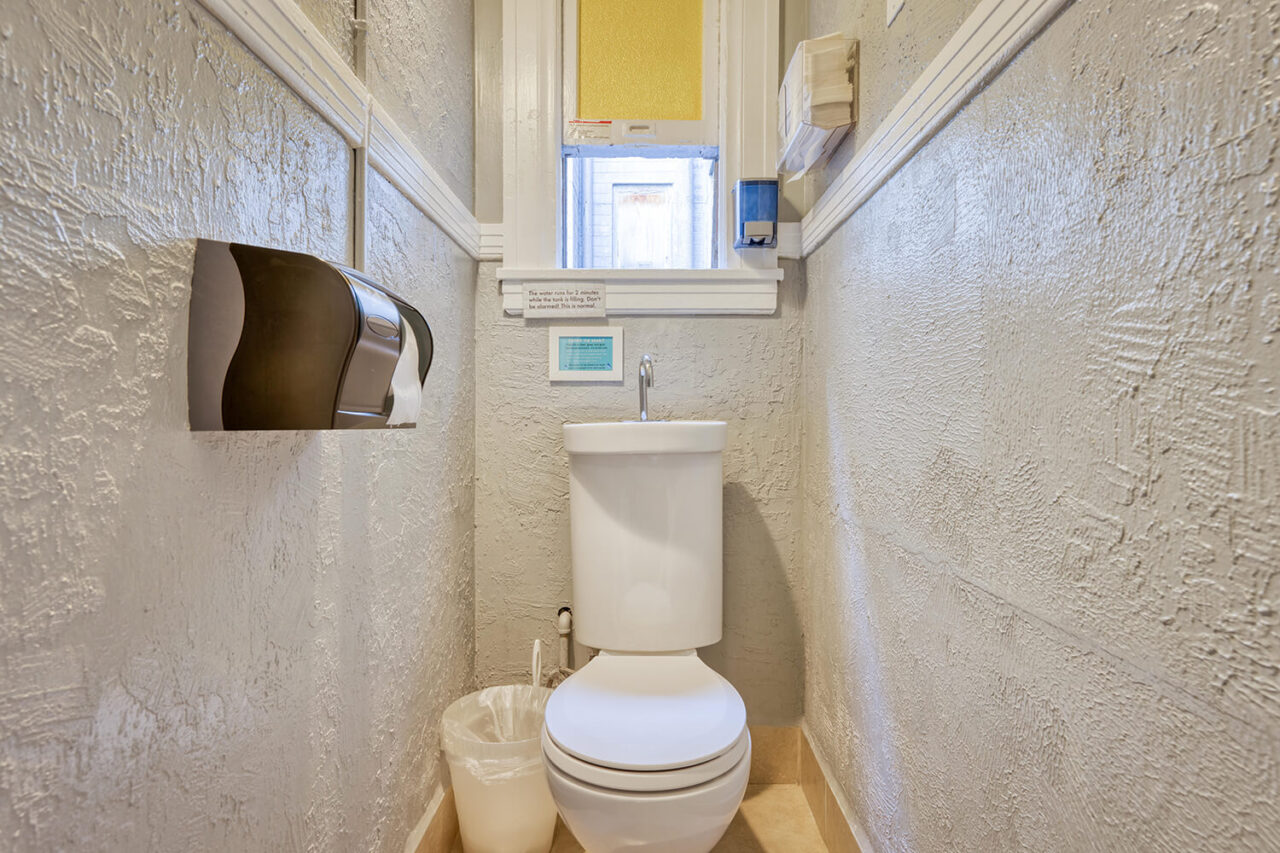 a small private restroom at HI San Francisco Downtown hostel with an eco-friendly system that uses recycled water from the sink to flush the toilet