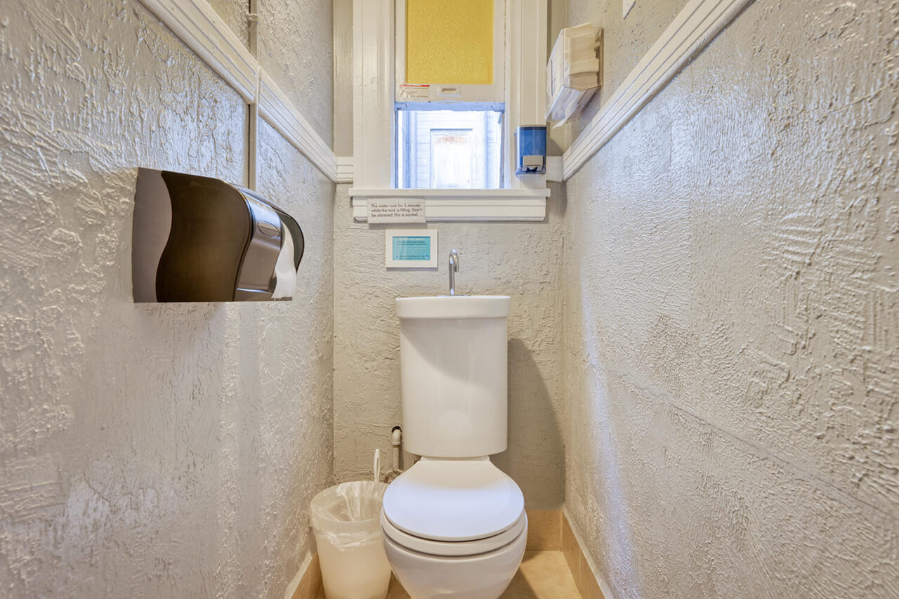 a small private restroom at HI San Francisco Downtown hostel with an eco-friendly system that uses recycled water from the sink to flush the toilet