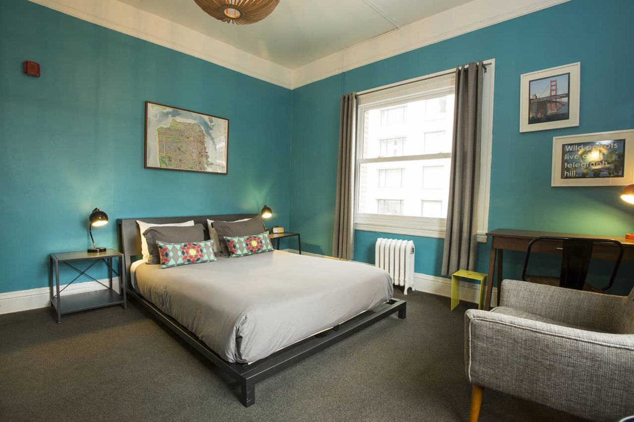 a queen-sized bed and arm chair in a private room at HI San Francisco Downtown hostel