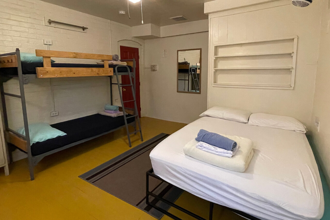 The Zuni room at HI Phoenix hostel, the Metcalf house, features an ensuite bathroom, one full-sized bed, and two twin-sized beds.