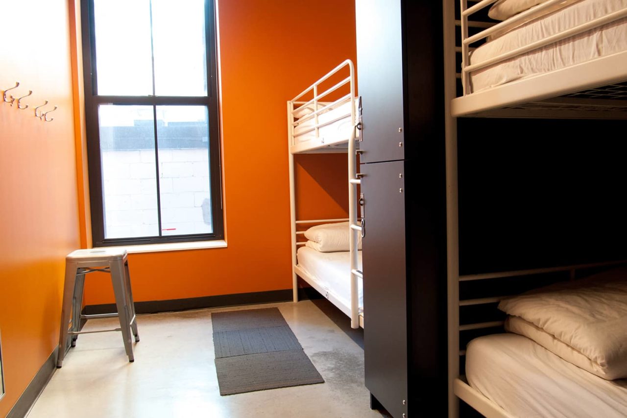 four twin-sized bunk beds with individual lockers in a room with orange walls
