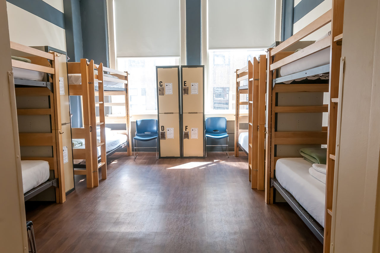 a large dorm room at HI Chicago hostel with four sets of twin-sized bunk beds, individual secure lockers for guest belongings, and plenty of natural light