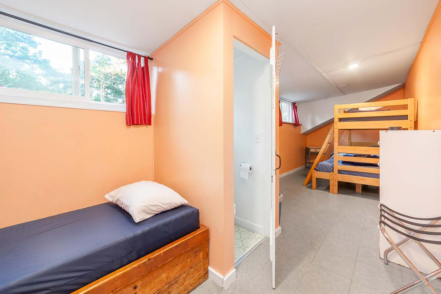 a private room at HI Martha's Vineyard hostel with one twin-sized bed, one twin-sized bed bunked over one full-sized bed, a luggage rack, and an ensuite half-bath