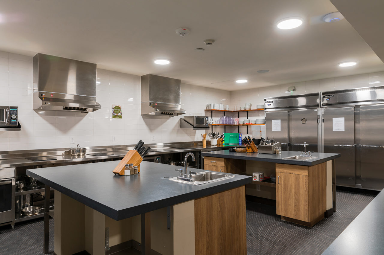 The fully equipped guest kitchen at HI New Orleans Hostel features everything you need to make your own meals on site, including two large kitchen islands, refrigerators, stoves, pots and pans, cutlery, and dishes.