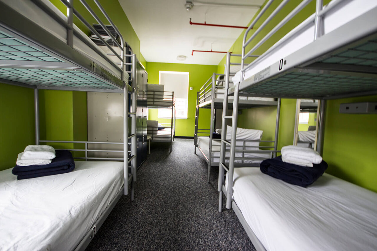A dorm room at HI New York City hostel with four sets of twin-sized bunk beds with crisp white linens.