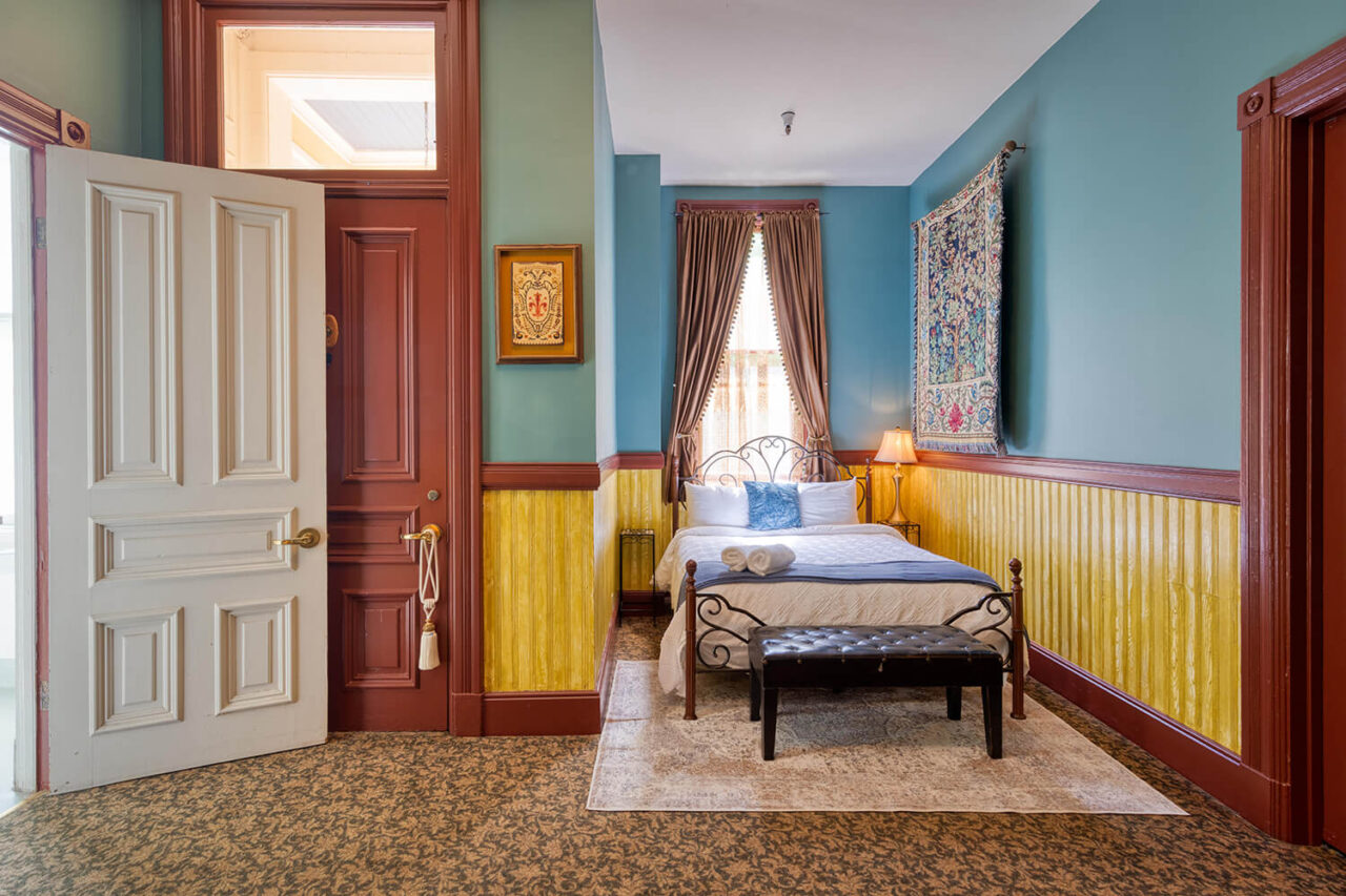 The private VIP queen room at HI Sacramento hostel features one queen-sized bed and a large seating area, plus en-suite bathroom