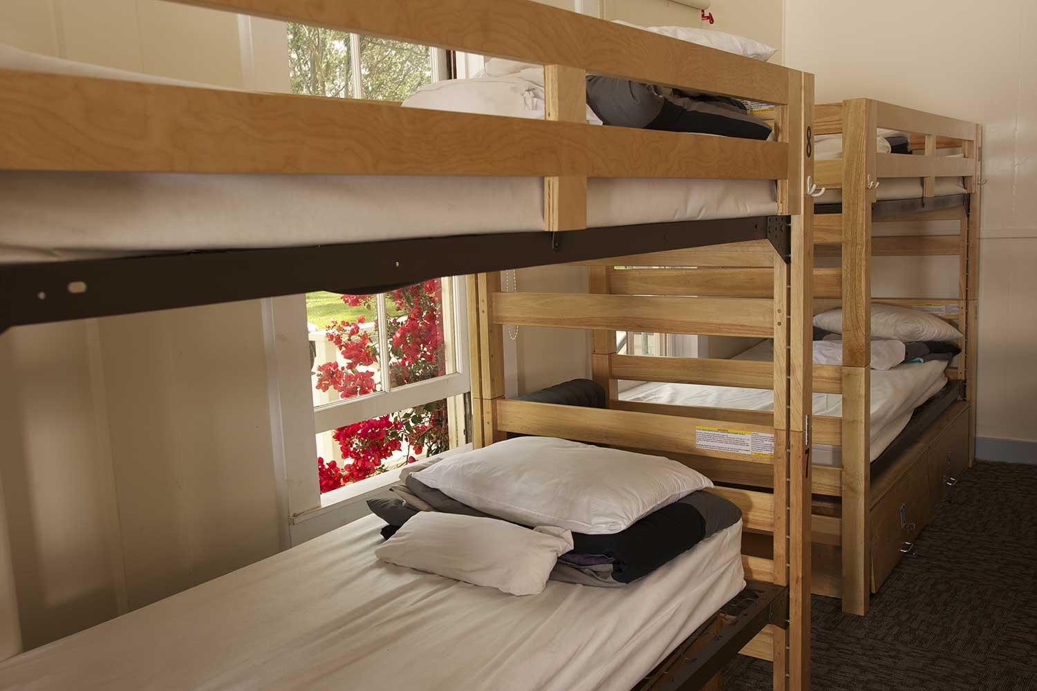 Small Dorm room at HI San Francisco Fisherman's Wharf hostel with two sets of freshly made bunkbeds next to a window