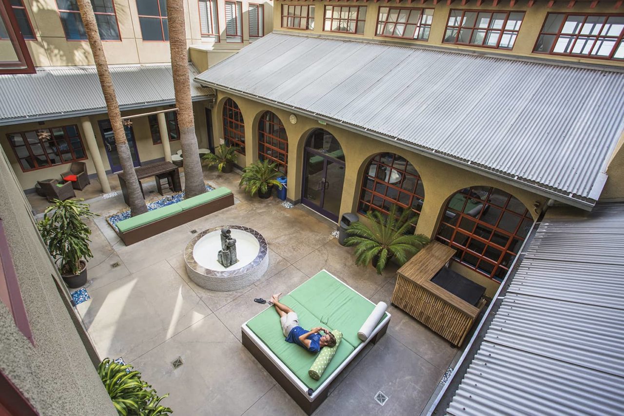an aerial view of a man relaxing in the sunshine in HI Los Angeles Santa Monica hotel's open interior courtyard