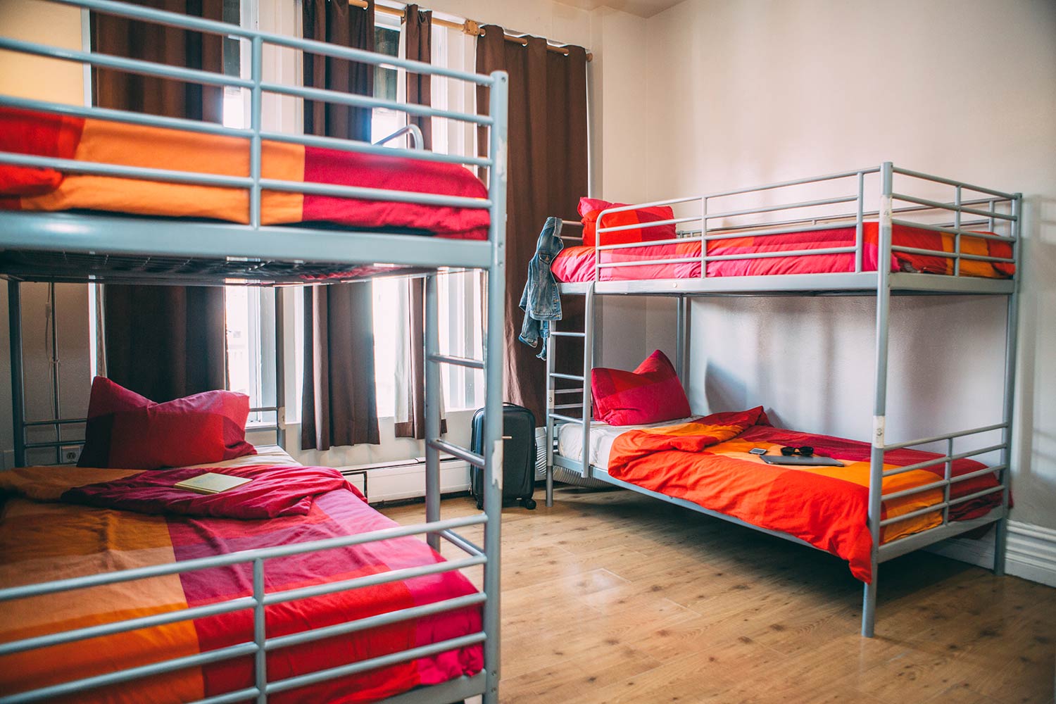 a small room at HI San Diego Downtown hostel with two sets of twin-sized bunk beds, each with freshly made orange-and-red-checkered linen.