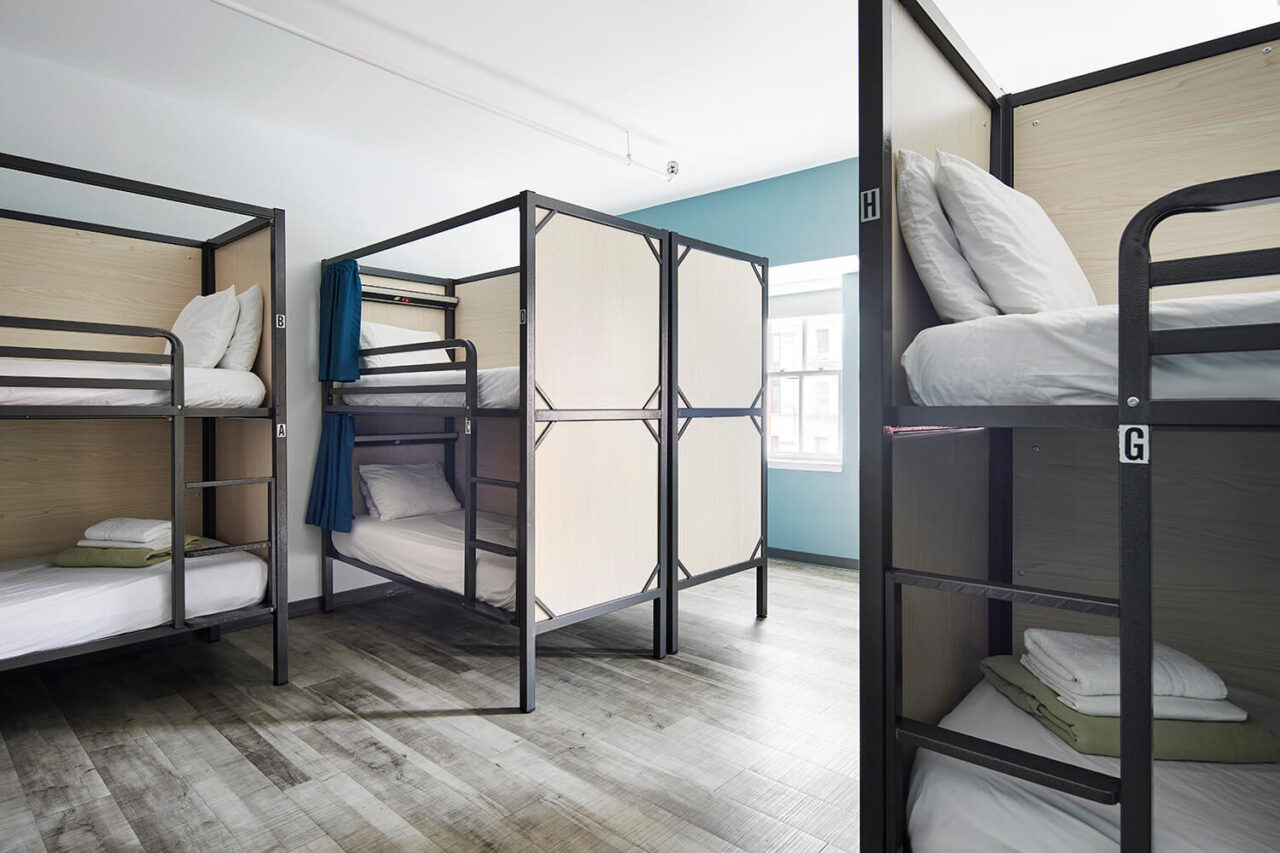 A spacious dorm room at HI New York City hostel with ten bunk beds. Each freshly made bed has a privacy screen, privacy curtain, reading light, and USB charging port.