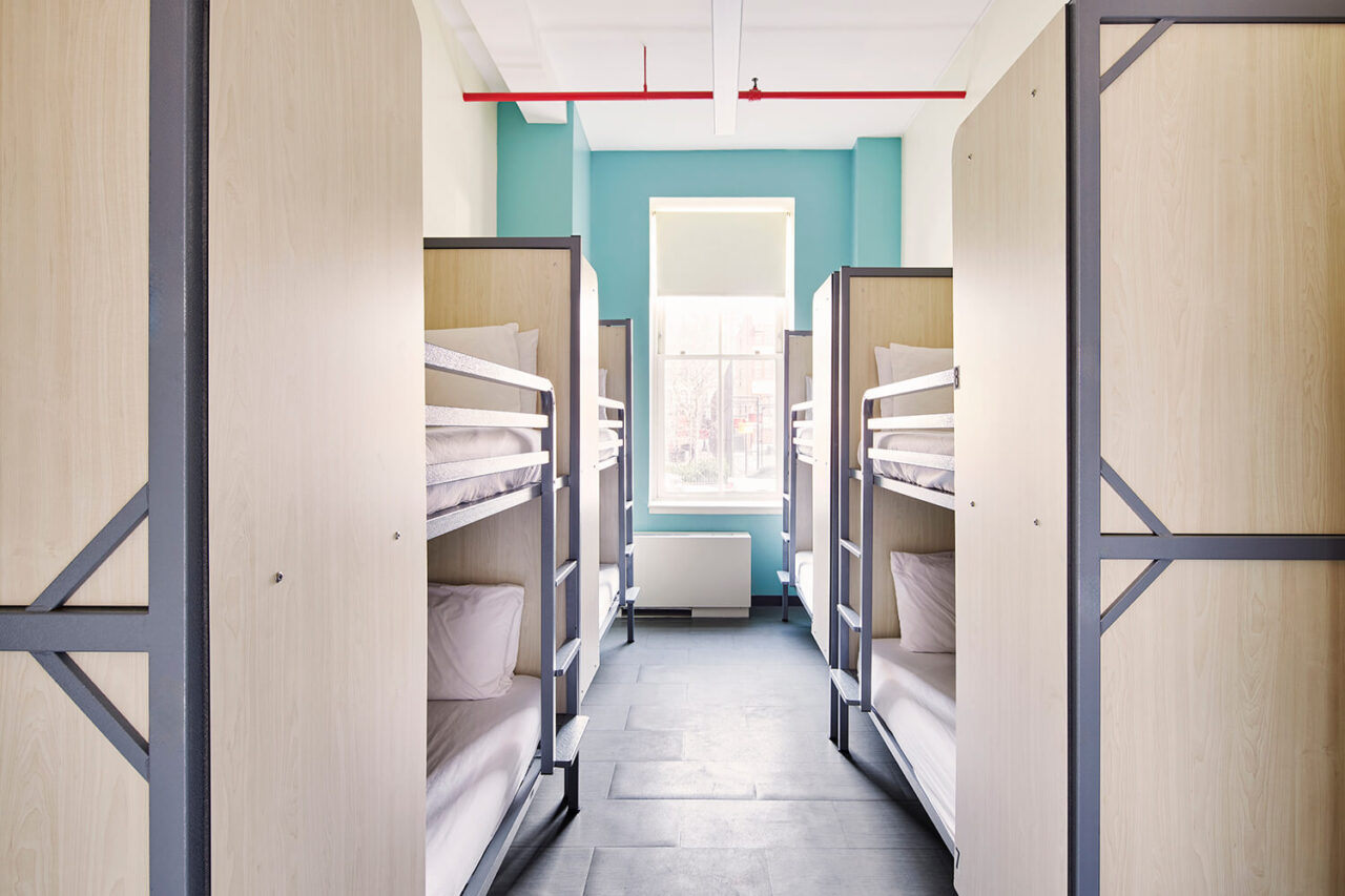 a clean and bright 8-bed dorm room at HI New York City hostel. Each of the four sets of new bunk beds has privacy screens, a reading light, and USB charging port.
