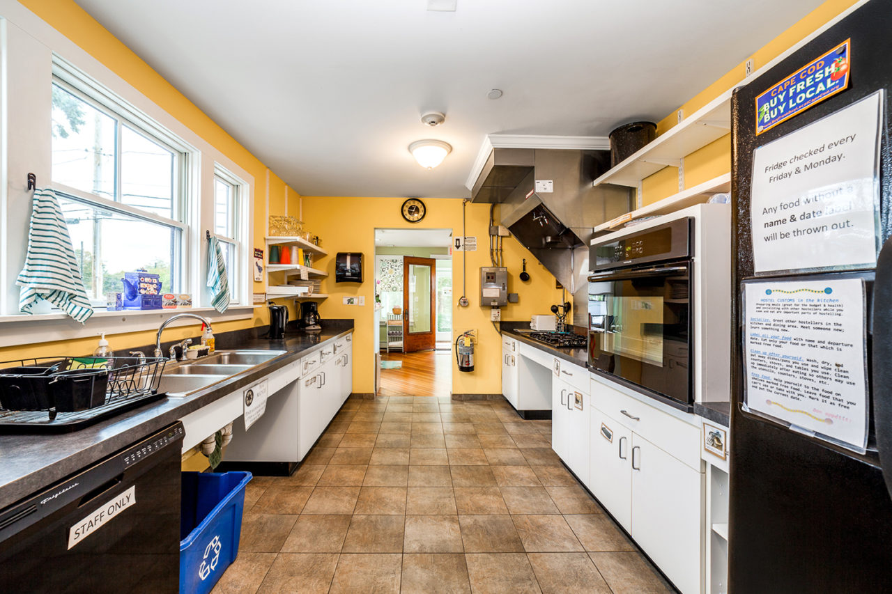 a kitchen with refrigerator, stovetops, cupboards, and sinks, and yellow walls