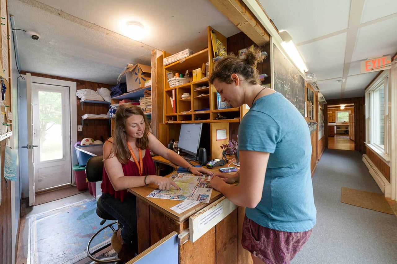 a friendly front desk agent at HI Martha's Vineyard hostel checks in a guest at the hostel's reception area