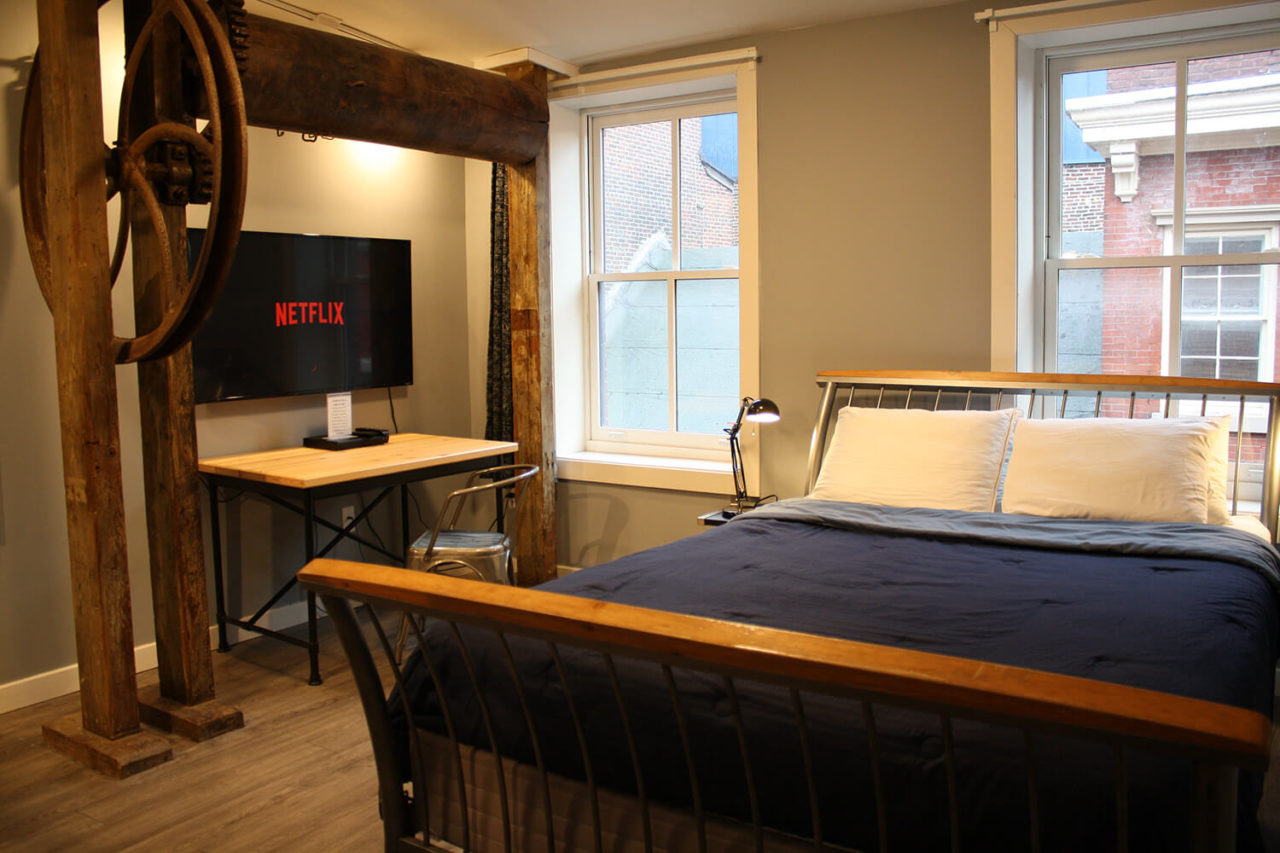a freshly made bed with a TV showing netflix in the background