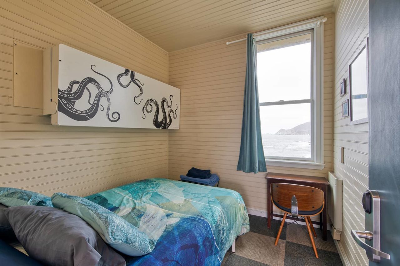 a freshly made full-sized bed overlooking the ocean