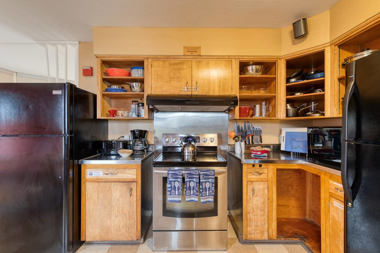 a stainless steel stove surrounded by cabinets and large refrigerators