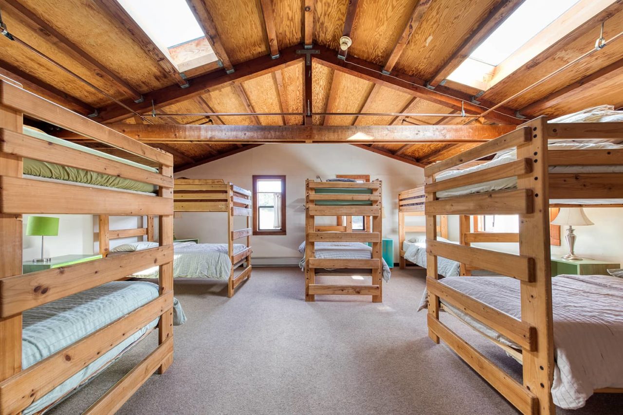 a spacious light-filled room with five sets of twin bunk beds