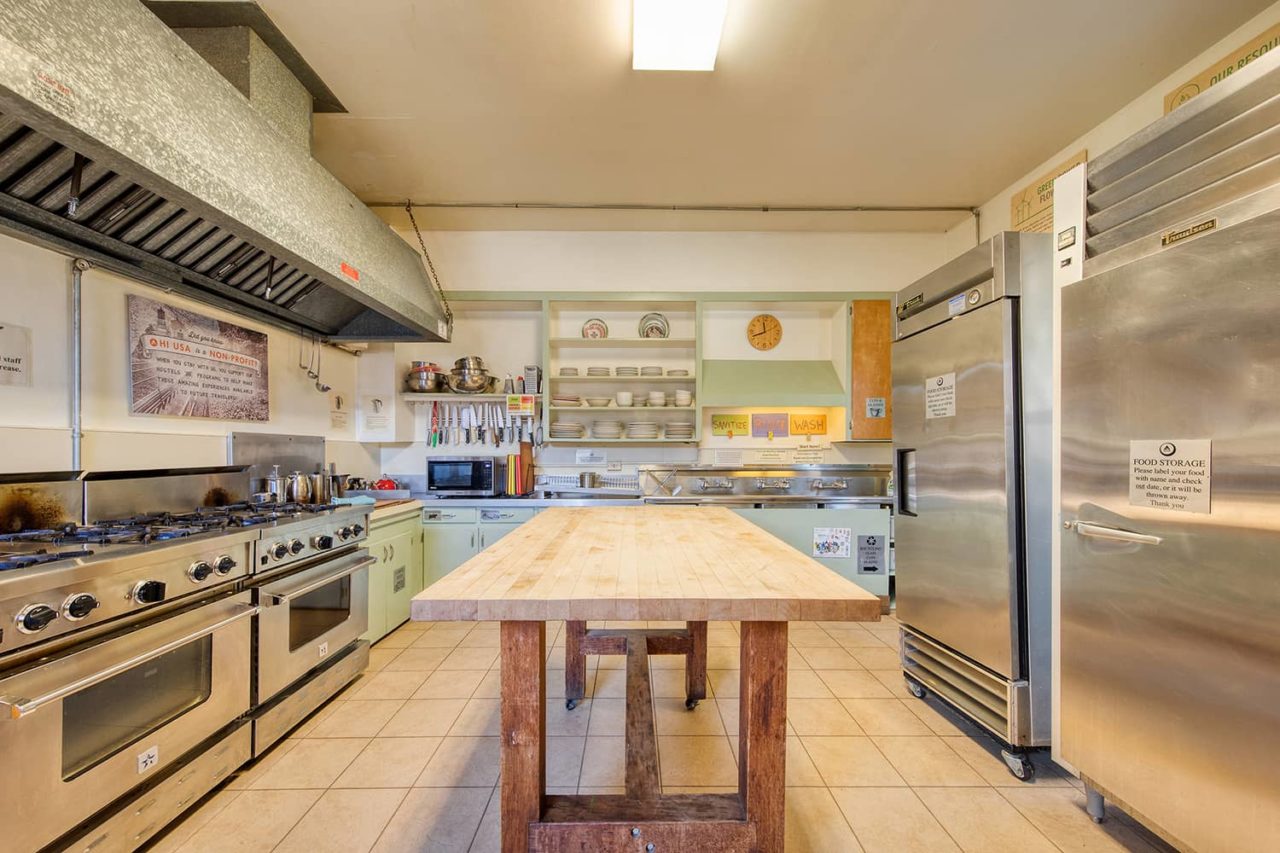 an open kitchen showing a large wooden kitchen island, two stoves, and a large stainless steel refrigerator
