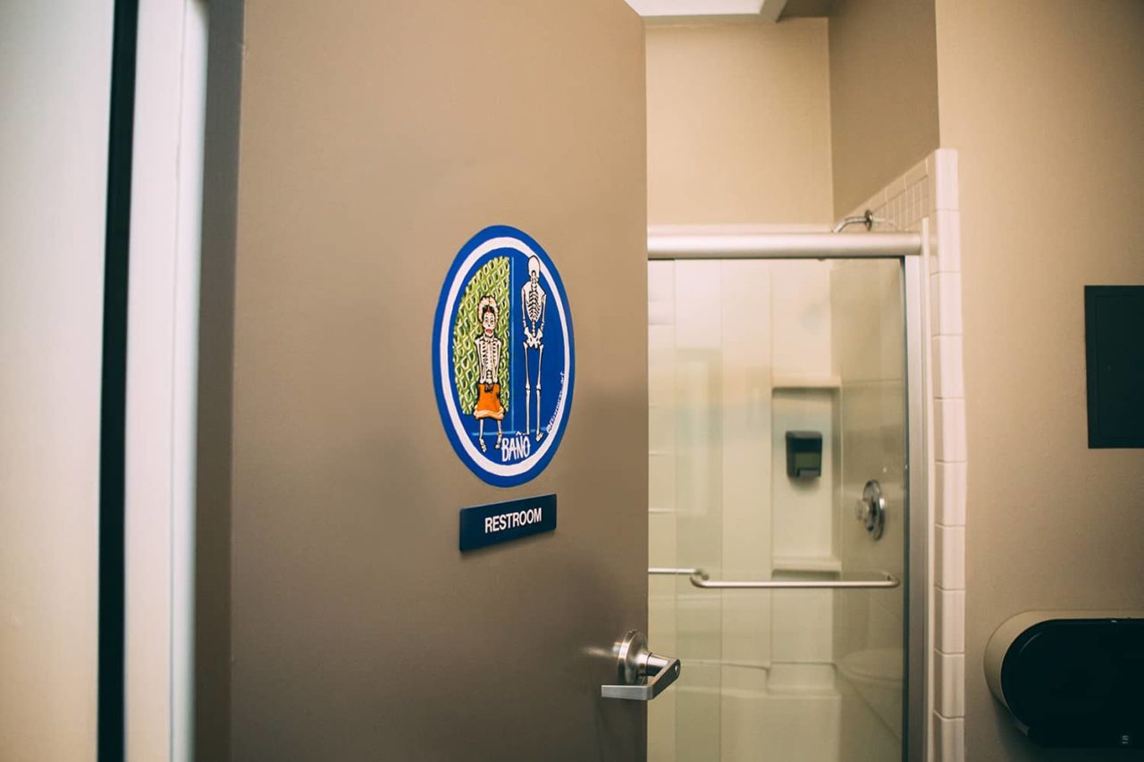 A hallway bathroom at HI San Diego downtown hostel containing a toilet, sink, and a shower. The bathroom locks from the inside to ensure security and privacy.