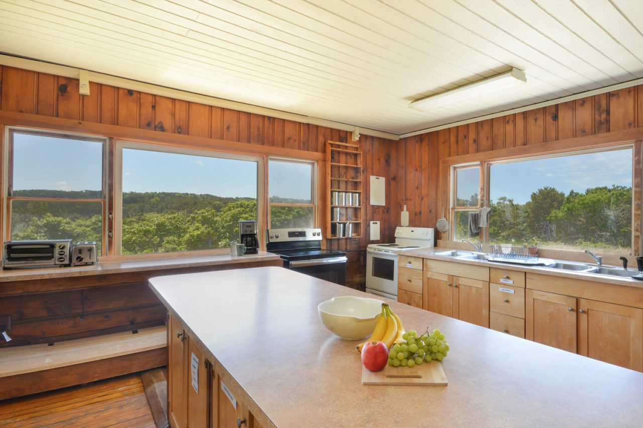 the guest kitchen at HI Truro hostel on Cape Cod. There is a large island countertop and large windows looking out over the landscape.
