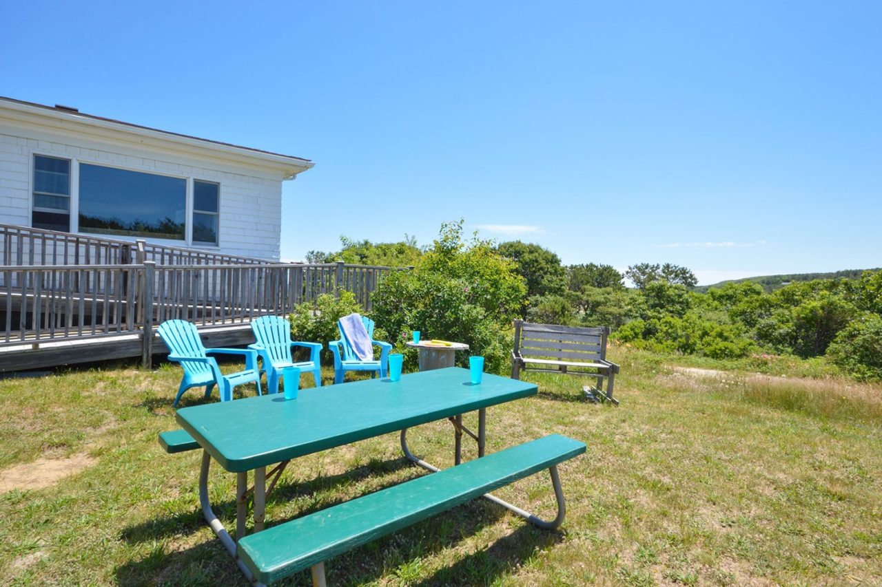 picnic tables and Adirondack chairs on a green lawn at HI Truro hostel on Cape Cod