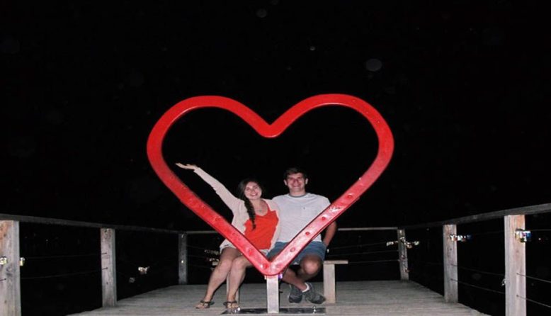 a couple posing with a heart sculpture