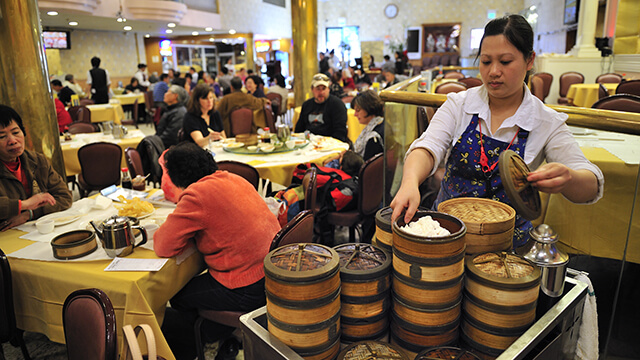 a crowded restaurant in San Francisco where diners sit at tables eating Dim Sum
