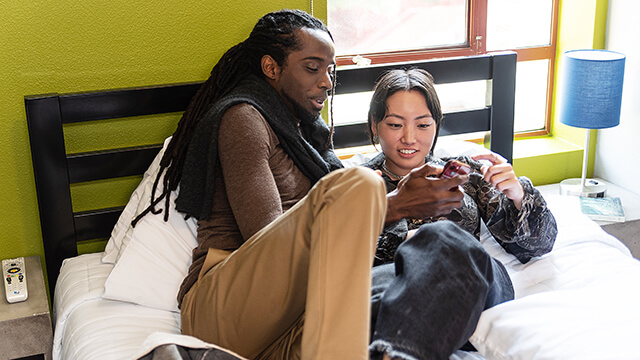 a couple relaxes on a large bed in a private room at HI Los Angeles Santa Monica hostel