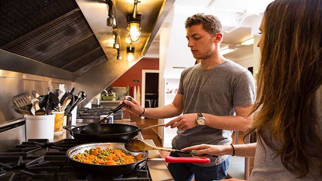 two hostel travelers making food