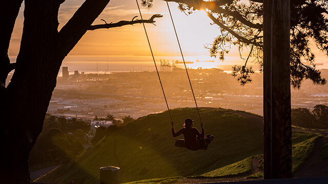 a person on a swing at sunset overlooking Bernal Hill in San Francisco