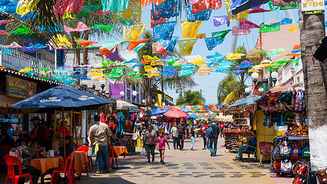 people walking down a street with colorful decorations in Tijuana, Mexico
