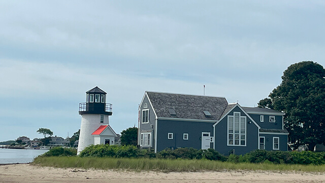 the small Hyannis Harbor lighthouse is seen from the water on a beach