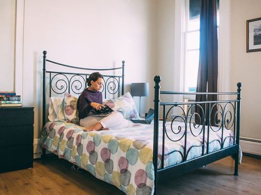 woman sitting on a bed in a private room at a hostel