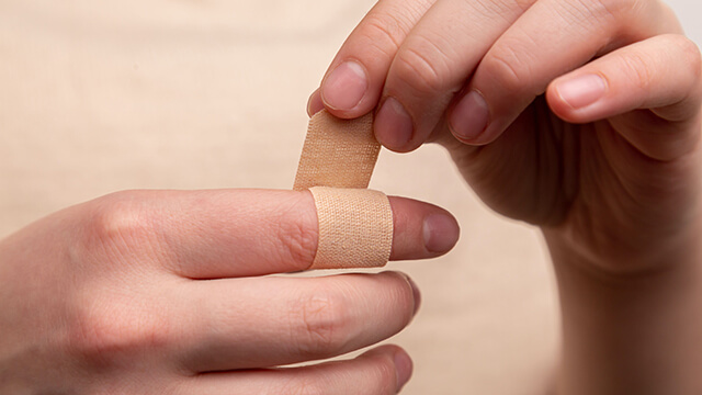 one hand wraps a bandage around the index finger of another hand