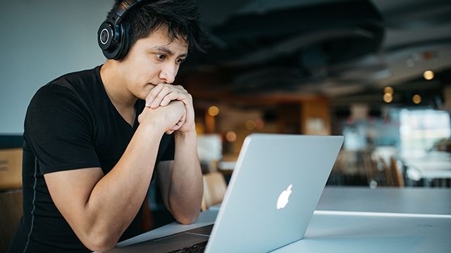 man looking at a laptop while wearing headphones