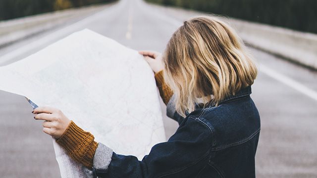 woman holding a map in the middle of a road