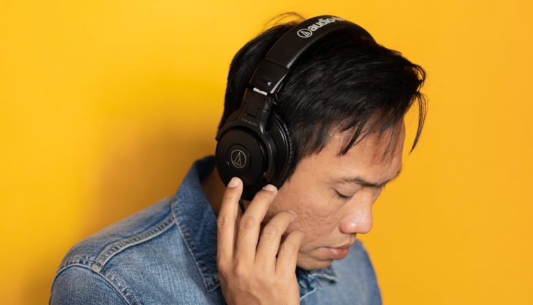 man with headphones against a yellow background